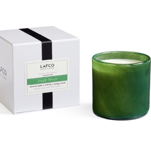 Green scented candle in a glass jar beside its white box