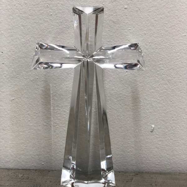 Clear glass cross figurine on a plain surface