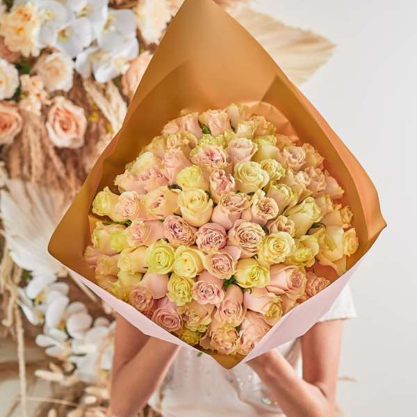 Large bouquet of pale pink and cream roses wrapped in tan paper