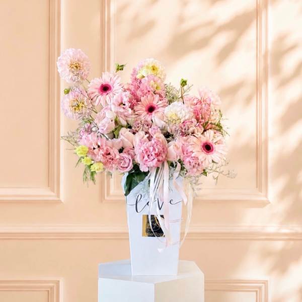 Pink mixed flower arrangement in a white gift box with ribbon