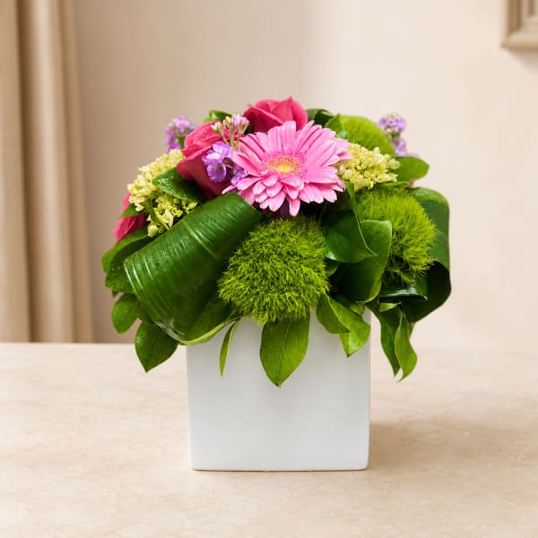 Pink gerbera and roses in a white square vase