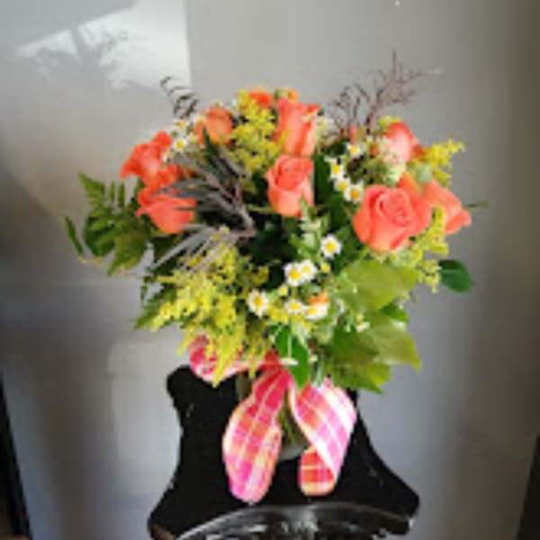 Coral rose bouquet with yellow filler flowers and a plaid ribbon