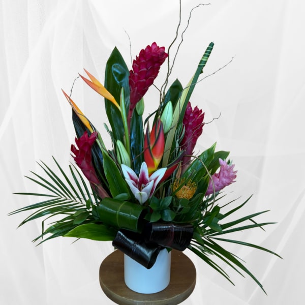 Tropical flower arrangement in a white vase with red and pink blooms