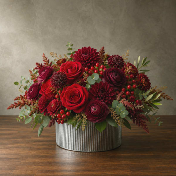 Red and burgundy flower arrangement in a ribbed metal container