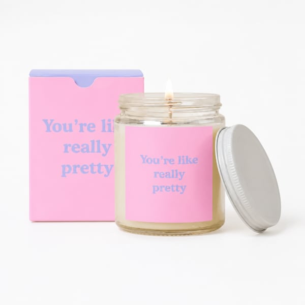 Pink candle jar with a lit wick and matching gift box