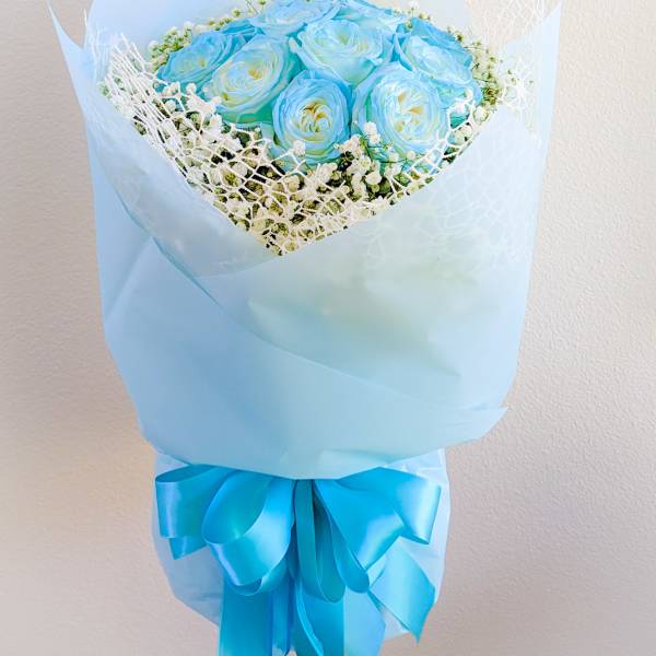 Bouquet of blue roses wrapped in pale blue paper with a ribbon