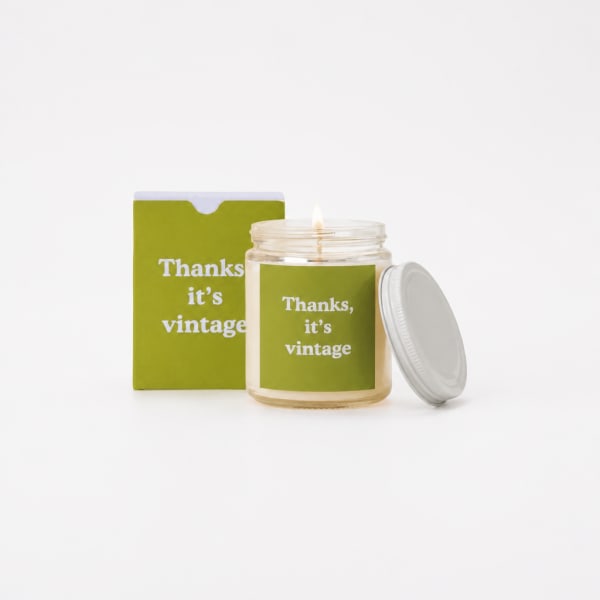 Lit candle in a glass jar with a matching box