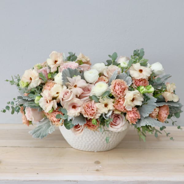 Blush and cream floral arrangement in a white textured bowl vase