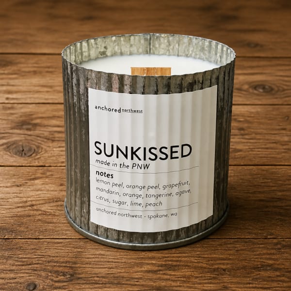 Scented candle in a rustic metal tin on a wooden surface