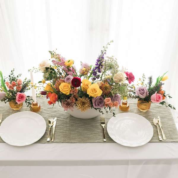 Floral table centerpiece with roses and mixed blooms on a dining table