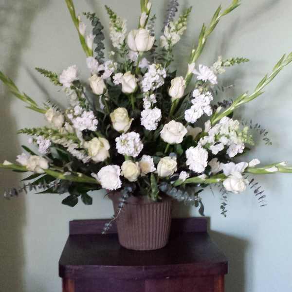 White floral arrangement in a ribbed vase with tall green spikes