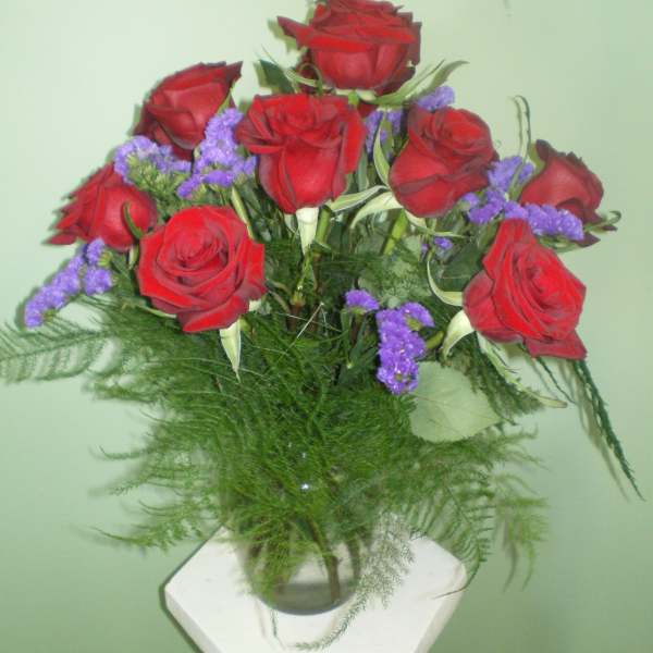 Bouquet of red roses with purple filler in a glass vase