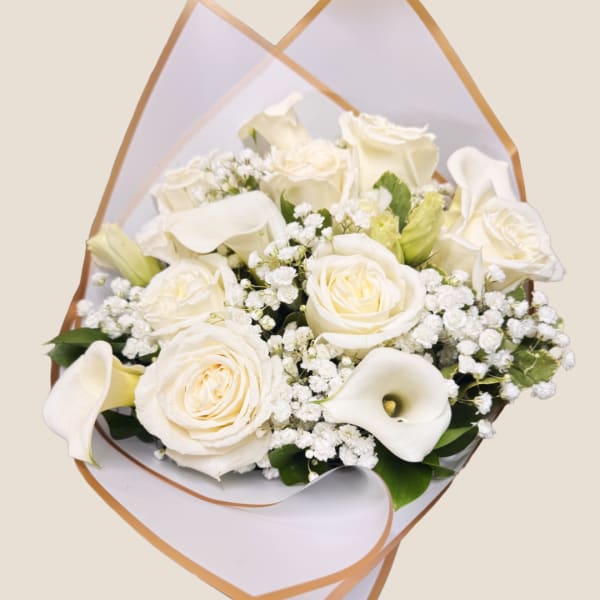 White roses and calla lilies in a wrapped bouquet