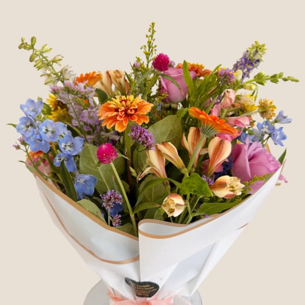Mixed bouquet of colorful flowers wrapped in white paper