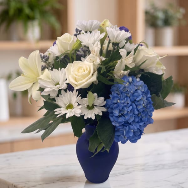 White and blue mixed bouquet in a dark blue vase