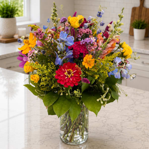 Colorful mixed bouquet in a clear glass vase on a kitchen counter