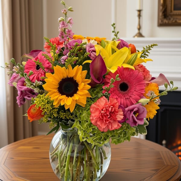 Colorful mixed bouquet with sunflowers, gerbera daisies, and lilies in a glass vase