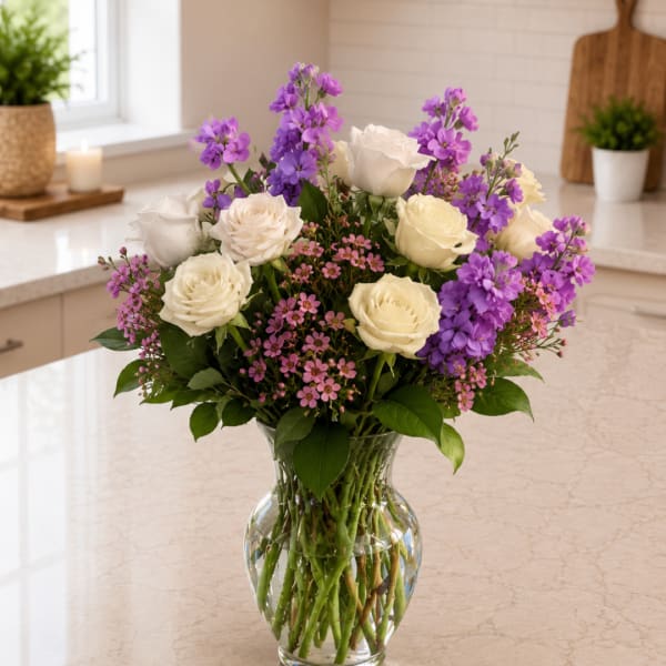 White and purple roses arranged in a clear glass vase