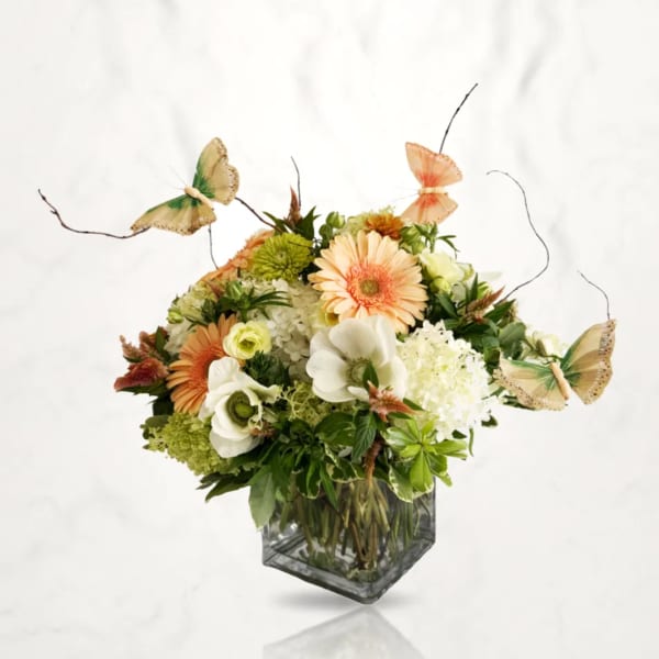 Mixed floral arrangement in a square glass vase with butterfly accents