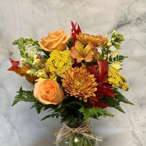 Bouquet of orange roses and yellow chrysanthemums in a glass vase