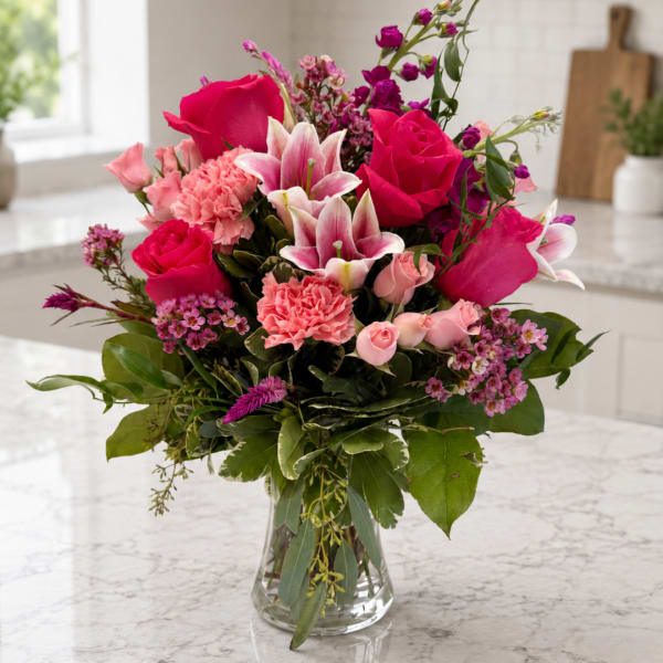 Pink and magenta mixed flower bouquet in a clear glass vase