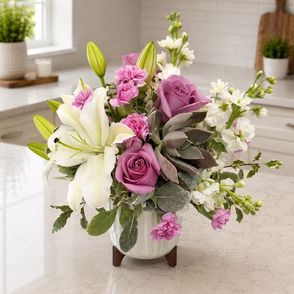 Pink and white floral arrangement in a white vase with lilies and roses