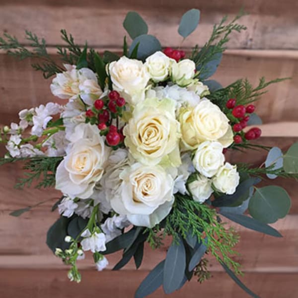 White rose bouquet with red berries and greenery