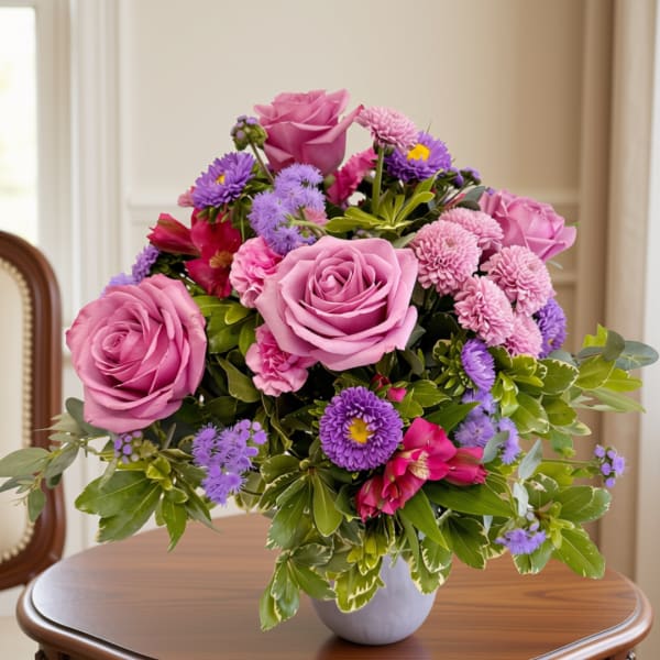 Pink roses and purple flowers arranged in a white vase