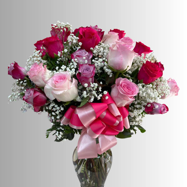 Bouquet of pink and red roses in a glass vase with a pink ribbon