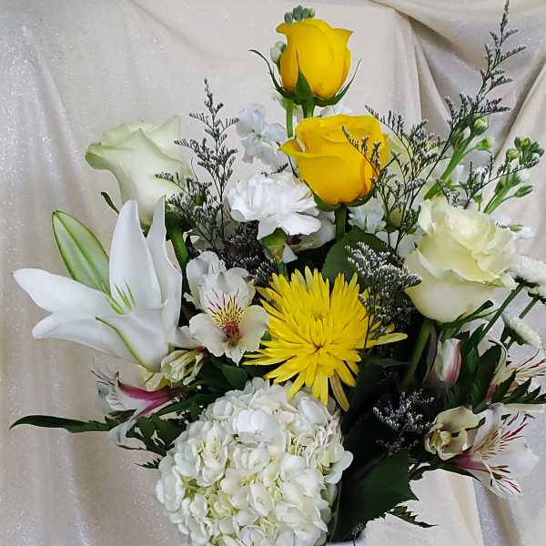 White vase arrangement with yellow and white flowers