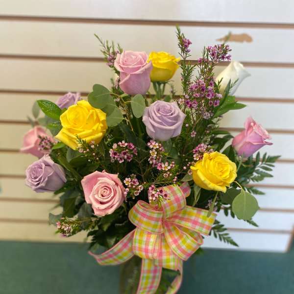 Bouquet of pink, yellow, and lavender roses with a plaid ribbon