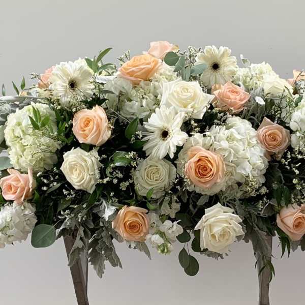 Large floral arrangement of peach and white roses with white blooms