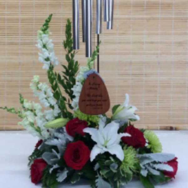 Red roses and white lilies arranged beneath a hanging wind chime