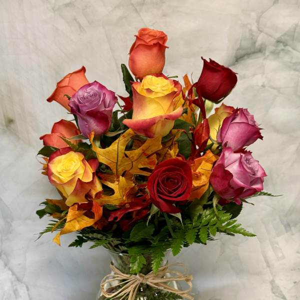 Mixed roses in a glass vase with autumn leaves