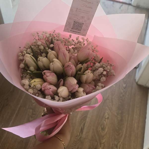 Pink and white tulip bouquet wrapped in pink paper with a ribbon