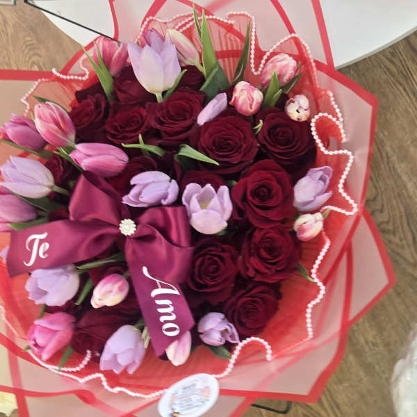 Bouquet of red roses and pink tulips wrapped in red paper