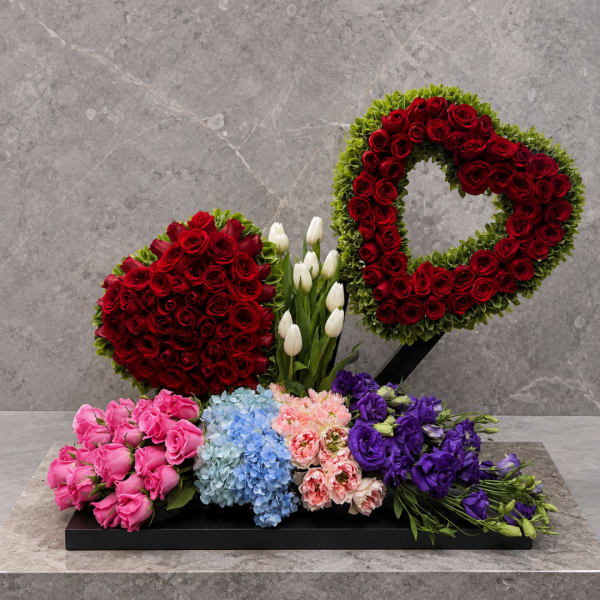 Heart-shaped red rose arrangement with tulips and mixed bouquets on a black base