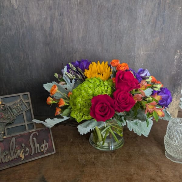 Mixed bouquet of roses, hydrangea, and bright blooms in a glass vase