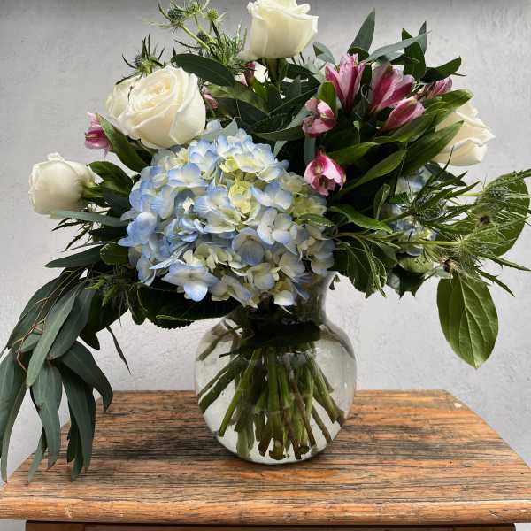 White roses and blue hydrangea in a glass vase