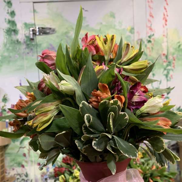 Mixed bouquet in a pink vase with a pink ribbon