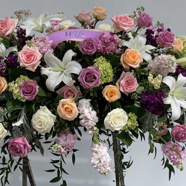Large casket spray with roses, lilies, and purple flowers