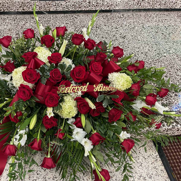 Large red and white floral funeral spray with ribbon and "Beloved Husband" sign