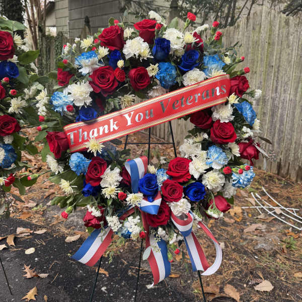 Red, white, and blue floral wreath on an easel with a thank-you ribbon