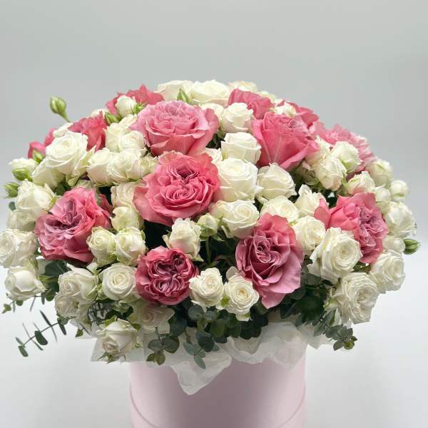 Pink and white roses arranged in a round pink box