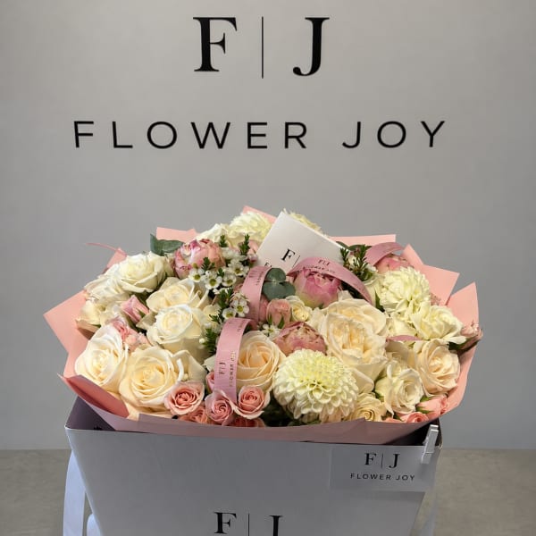 Bouquet of cream and blush roses with pale dahlias in a gift box