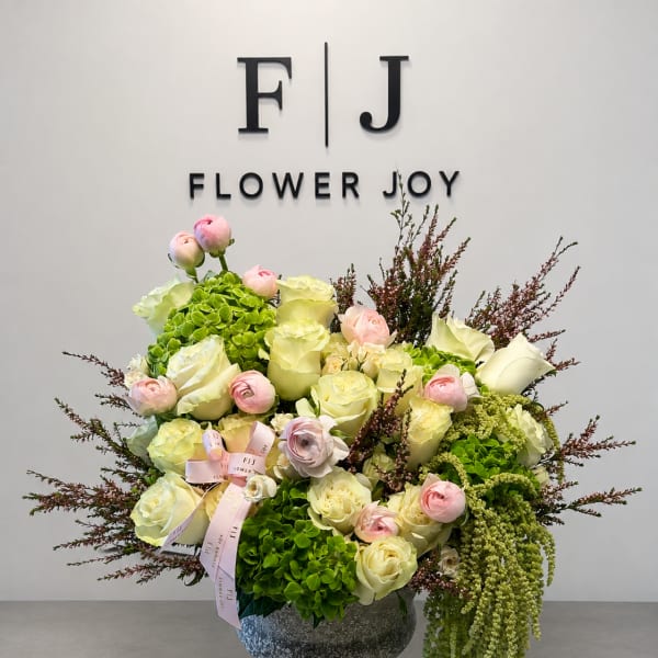 Bouquet of cream and pink roses with green hydrangeas in a gray vase