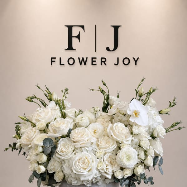 White rose arrangement in a gray vase with eucalyptus accents