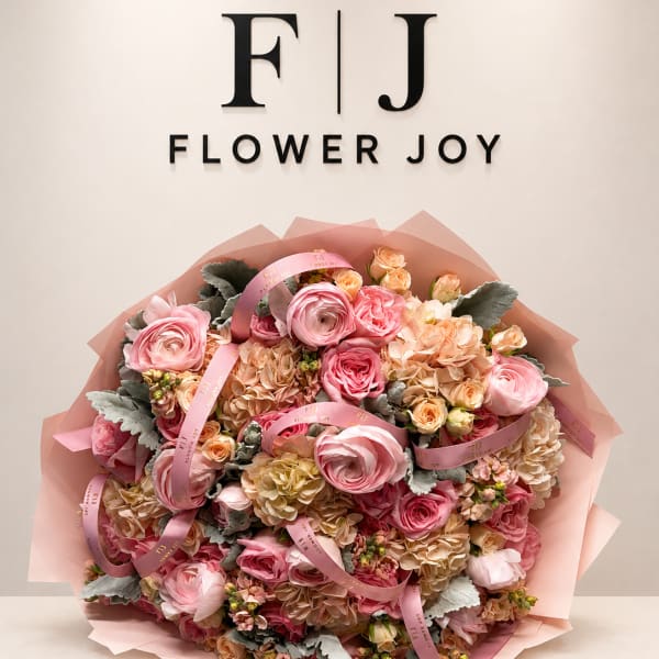 Large pink bouquet of roses, ranunculus, and hydrangeas wrapped in pink paper