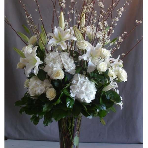 White lilies and roses arranged in a tall glass vase