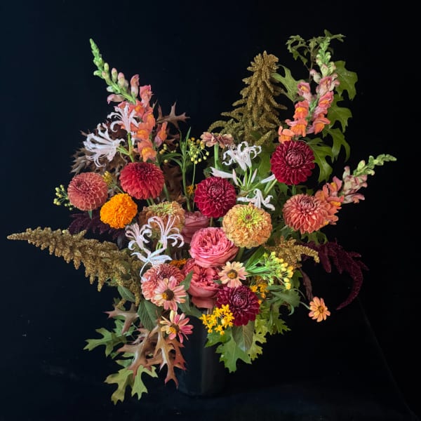 Mixed autumn bouquet in a black vase with dahlias, snapdragons, and white spider lilies